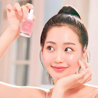 Anua Peach 70 Niacin Serum 30mL in a clear glass bottle with a white dropper cap, set against a white background.
