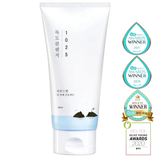 Round Lab 1025 Dokdo Cleanser cleansing foam in a white tube with blue accents, shown next to a small bowl of foam.