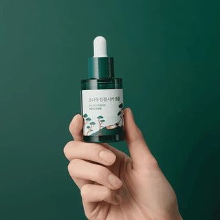 Bottle of ROUND LAB Pine Calming Cica Ampoule 30mL, a soothing facial skincare product with calming ingredients.