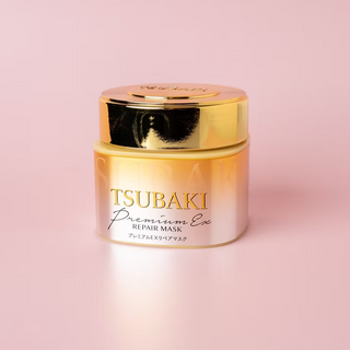 Shiseido Tsubaki Premium EX Repair Hair Mask 180g jar with floral design, showcasing shiny, healthy hair.